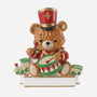 Toy soldier bear ornament with a teddy bear in a red and gold uniform playing a drum, with toy train accents along the base.