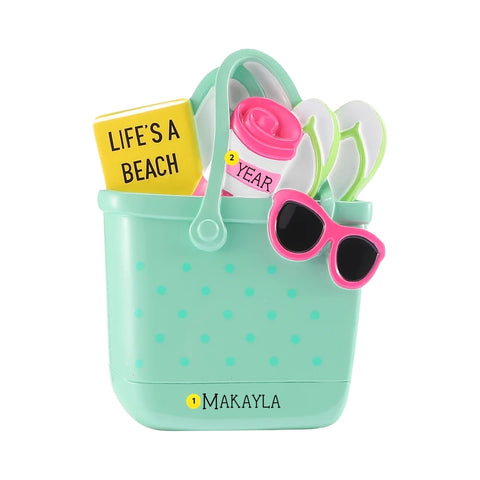 Personalized trendy rubber beach bag ornament with a name on the bag and the year written on the beach towel.