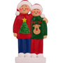 Christmas-themed couple ornament wearing sweaters with tree and reindeer designs on a white background.