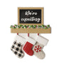 “We’re expecting” mantel ornament with three hanging stockings, greenery garland, a black sign, and space for personalization along the mantel and stocking cuffs.