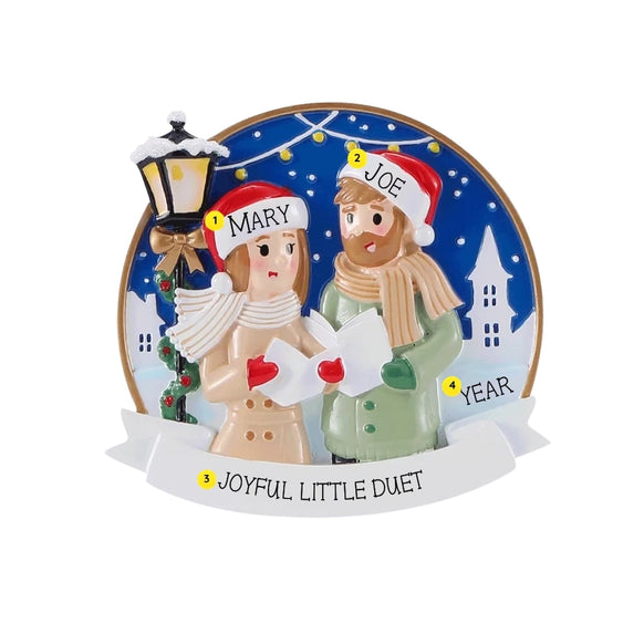 Personalized winter caroling couple ornament with names on the hats, a phrase on the front banner, and space for a year.