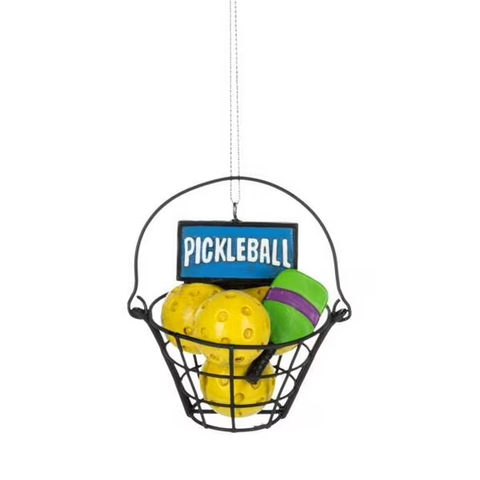 Pickleball ornament with a black wire basket holding yellow pickleballs, colorful paddles, and a blue pickleball sign.