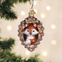 Fox ornament in a pine cone on a Christmas tree with lights in the background