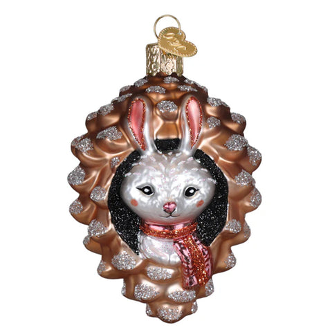 Decorative glass ornament of a rabbit with a pink scarf in a pinecone on a white background