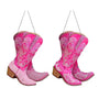 Two pink rhinestone cowboy boot ornaments with scrolling decorative details, wood-look heels, and black hanging cords.