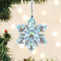 Iridescent snowflake ornament hanging on a Christmas tree with blurred lights in the background.