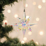 Iridescent star-shaped Christmas ornament on a tree with blurred lights in the background