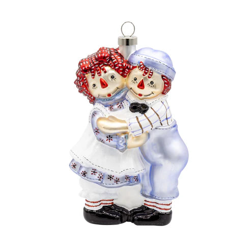 Glass Raggedy Ann & Andy Holiday Hug ornament featuring the classic dolls hugging face to face in blue and white outfits.