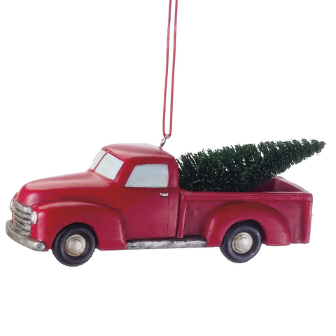 Red pickup truck ornament carrying a green Christmas tree in the bed, styled with a vintage look and hanging loop above.