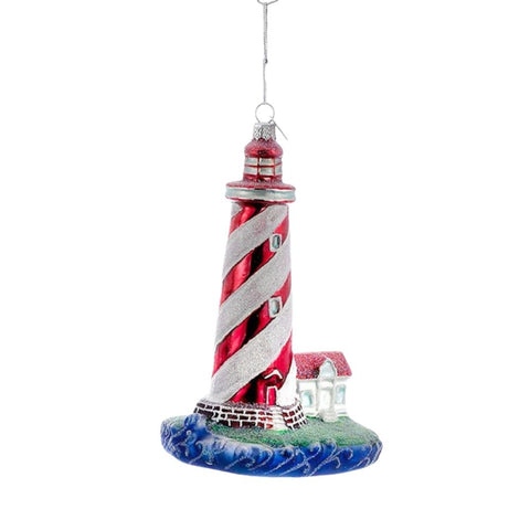 Red and white striped lighthouse ornament with spiral tower design, small coastal cottage, ocean wave base, and silver hanging cord.