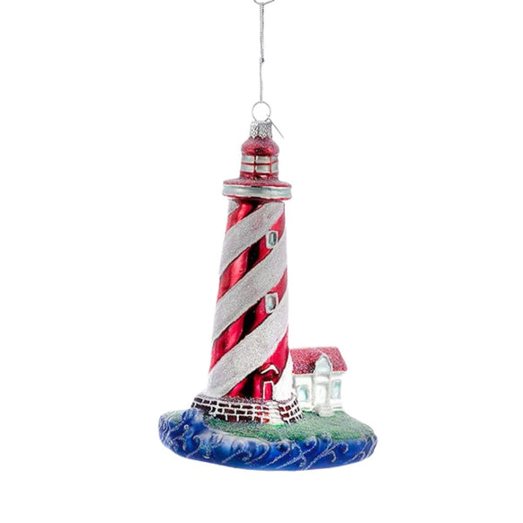 Red and white striped lighthouse ornament with spiral tower design, small coastal cottage, ocean wave base, and silver hanging cord.