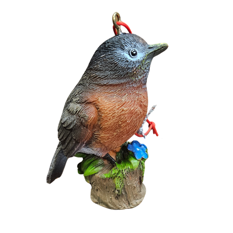 Robin ornament with warm brown chest and gray-brown feathers perched on a tree stump with green leaves and a blue flower.