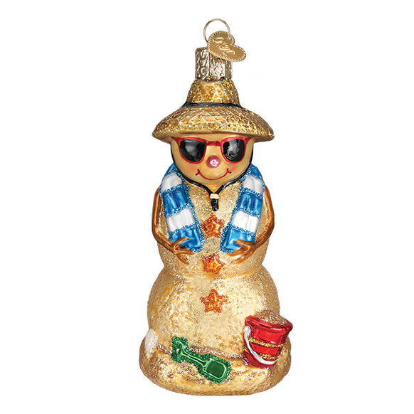 Glass ornament of a sandman with a straw hat, sunglasses, and a blue scarf on a white background.