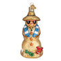 Glass ornament of a sandman with a straw hat, sunglasses, and a blue scarf on a white background.