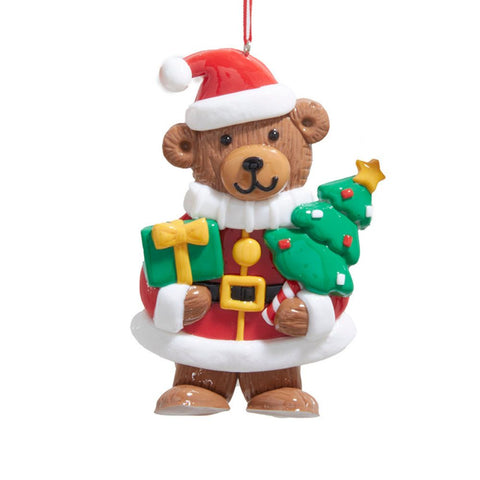 Bear ornament dressed in a red Santa coat and hat, holding a green wrapped gift and a decorated Christmas tree.