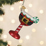 Decorative glass candy cane ornament with Santa hat on a blurred Christmas tree background.