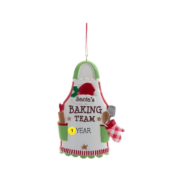 Santa’s Baking Team apron ornament with a Santa hat, rolling pin, baking tools, festive red and green details, and sample year personalization.