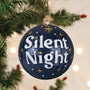 Decorative ornament with 'Silent Night' text on a Christmas tree.