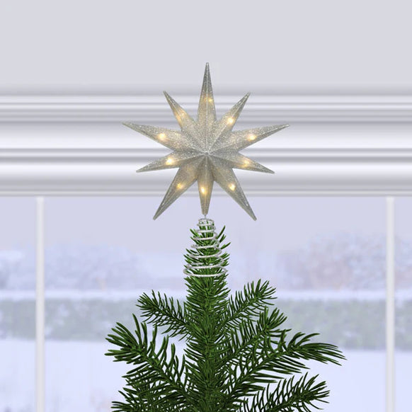 12" silver glitter star treetop lit on a Christmas tree in front of a snowy window scene.