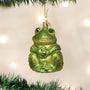 Green frog ornament hanging on a Christmas tree with lights in the background