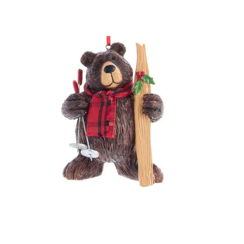 Brown bear ornament wearing a red plaid scarf and holding skis and ski poles.