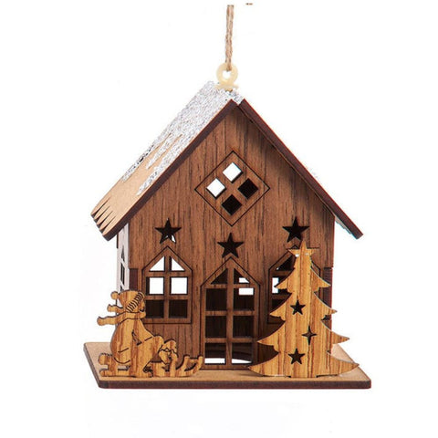 Wooden cottage ornament with a snowy roof, front windows, a child on a sled, and a cutout tree beside the house.