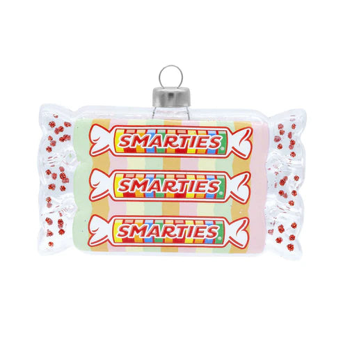 Glass Smarties candy ornament shaped like a wrapped roll of candy with printed Smarties labels and red glitter accents.