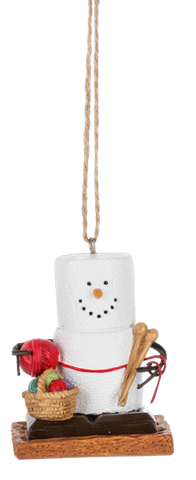 S’mores Knitting ornament featuring a marshmallow snowman-style figure on a graham cracker base with knitting needles, yarn, and a basket of craft supplies.