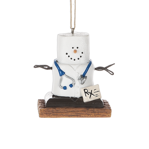 S’mores medical ornament featuring a marshmallow character in a white doctor coat with a blue stethoscope and prescription pad, standing on a graham cracker base.