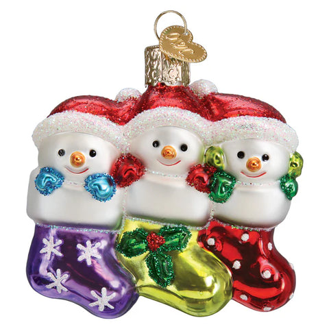 Three glass snowman ornaments in colorful stockings with Santa hats on a white background