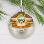 Decorative ornament of Baby Yoda in a metallic pod with greenery in the background