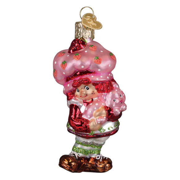 Glass ornament of a strawberry shortcake character with pink whipped cream and strawberries on a white background