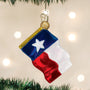 Texas flag ornament hanging on a Christmas tree with lights in the background