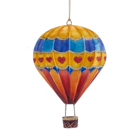 Tin hot air balloon ornament with blue, yellow, orange, and red panels, a glittered heart band, and a small hanging basket.