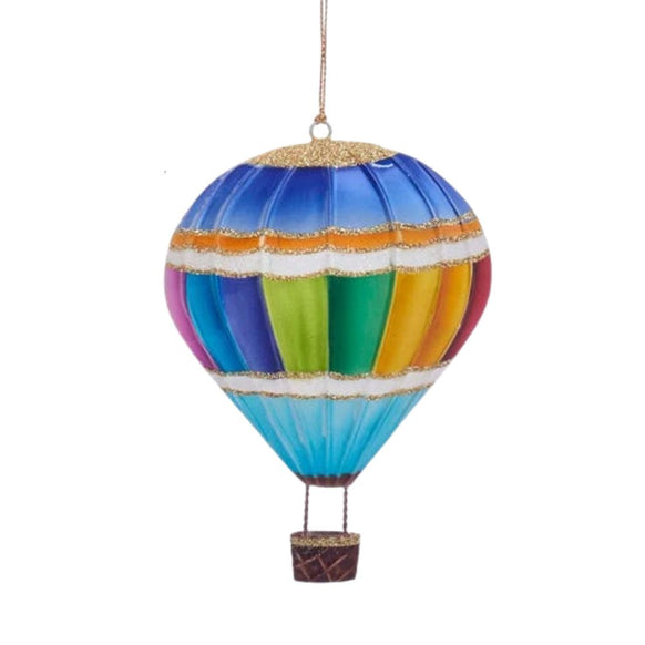 Tin hot air balloon ornament with rainbow vertical stripes, blue top and base, gold glitter trim, and a small hanging basket.