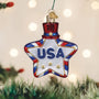 Star-shaped 'USA' ornament on a Christmas tree with blurred lights in the background