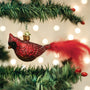 Red glass cardinal ornament on a Christmas tree with lights in the background
