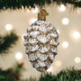 Decorative glass pine cone ornament on a Christmas tree with blurred lights in the background