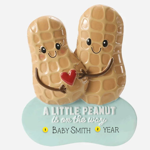 Decorative ornament with cartoon peanuts holding a heart, featuring text 'A Little Peanut is on the way' and  can be personalized.