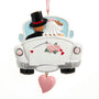 Wedding car ornament featuring a bride and groom in a white getaway car with pink roses, red heart details, and a dangling pink heart accent.