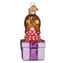 Decorative glass ornament of a person with a checkered dress on a purple box against a white background