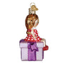Glass ornament of a girl in a red dress sitting on a present with gold hair.