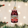Smucker's Strawberry Jam jar ornament hanging on a Christmas tree with lights in the background.
