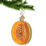 Cantaloupe Ornament sliced open hanging by a gold swirl hook from a Christmas tree branch