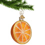 Glass Orange half ornament hanging by a gold swirl hook from a Christmas tree branch