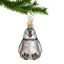Glass penguin chick ornament hanging from a gold swirl hook on a Christmas tree branch