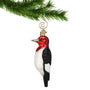 Glass Woodpecker Ornament with Red Head, White body and black back hanging from a gold swirl hook on a Christmas tree branch