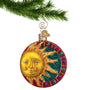 Glass Sun Ornament with Jewels on a red circle border hanging by a gold swirl hook from a Christmas tree branch