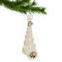 White Twisted like a staircase Sea Shell Glass Christmas Ornament hanging from a gold swirl hook on a Christmas tree branch