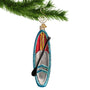 Glass Paddle Boarding Ornament hanging by a gold hook from a Christmas tree branch
